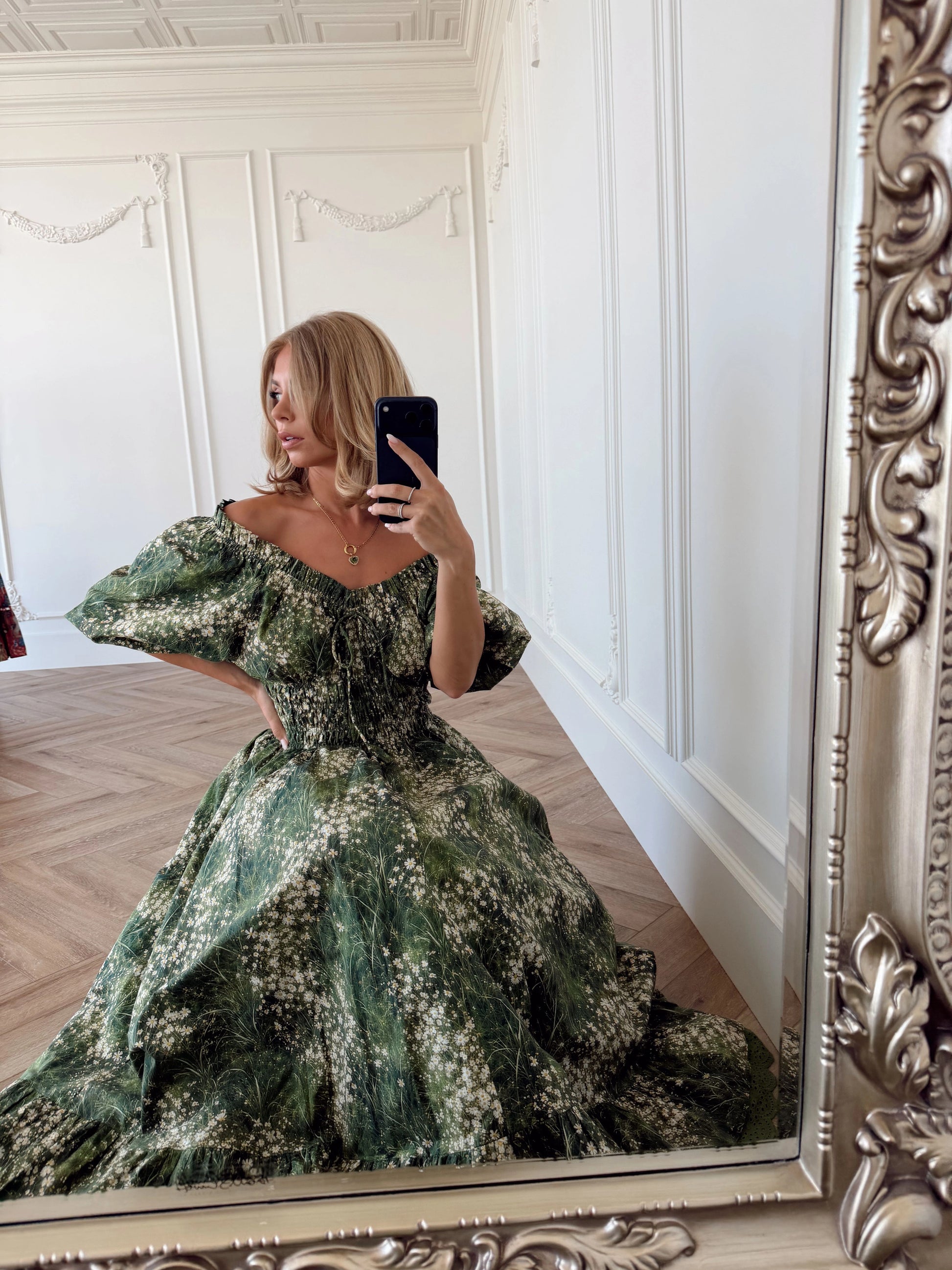 A woman in a dress taking a picture of herself in a mirror